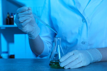 Laboratory testing. Scientist dripping sample into flask at table indoors, closeupの写真素材