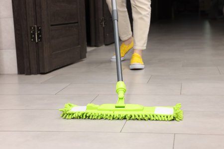 Woman cleaning floor with microfiber mop indoors, closeup