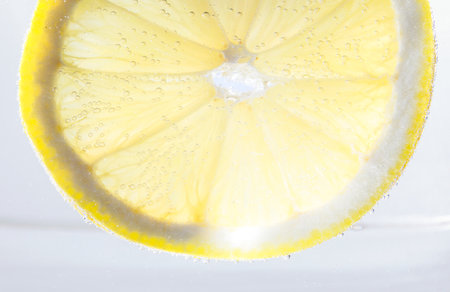 Soda water with lemon slice against white background, closeupの写真素材