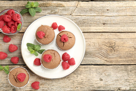 Delicious muffins with raspberries and mint on wooden table, flat lay. Space for textの写真素材