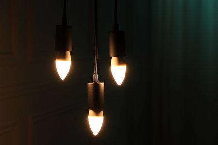 Glowing light bulbs hanging indoors, space for textの写真素材