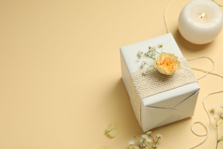Florist. Box, flowers and burning candle on beige background, space for textの写真素材