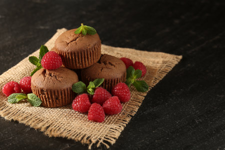 Muffins with raspberries and mint on dark textured table, closeup. Space for textの写真素材