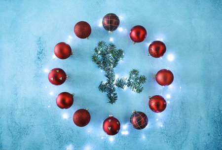Clock made with Christmas decor and fir tree branches on blue background, flat lay
