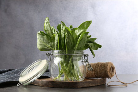 Fresh sorrel in glass jar and twine on grey table, closeupの写真素材