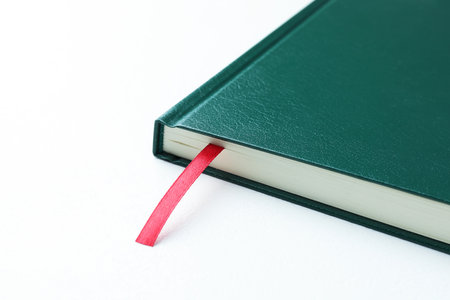 Book with red ribbon bookmark on white table, closeup. Space for textの写真素材