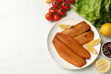 Delicious smoked herring fillets with lemon slices and other products on white table, flat lay....