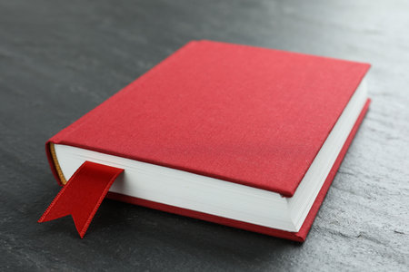 Book with red ribbon bookmark on dark textured table, closeupの写真素材