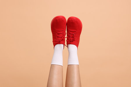 Woman wearing stylish sneakers on beige background, closeupの写真素材