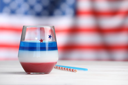 Tasty cocktail in glass and straws on white wooden table against flag of USA, space for textの写真素材