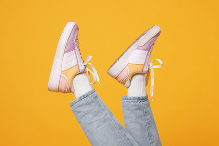 Woman wearing stylish sneakers on orange background, closeupの写真素材