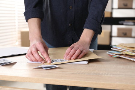 Woman putting barcode onto envelope at table in post office, closeupの写真素材