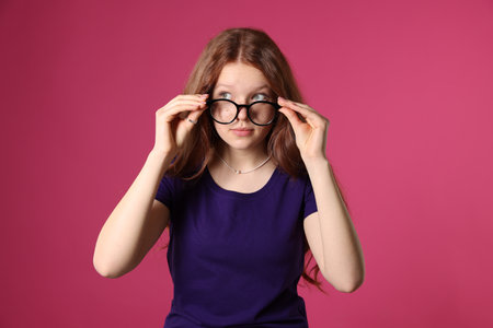 Beautiful freckled teenage girl with glasses on pink backgroundの写真素材