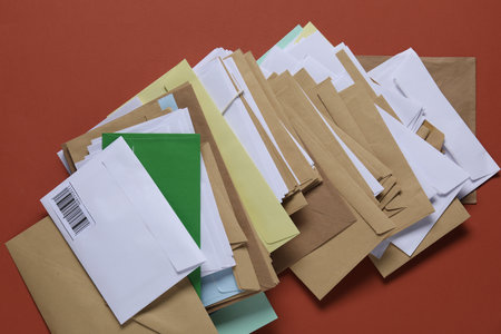 Different paper envelopes on red-brown background, top view. Post officeの写真素材