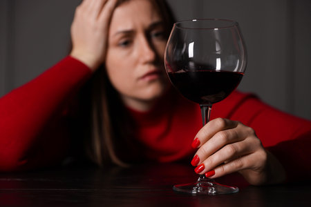 Woman with glass of red wine at wooden table indoors, selective focusの写真素材
