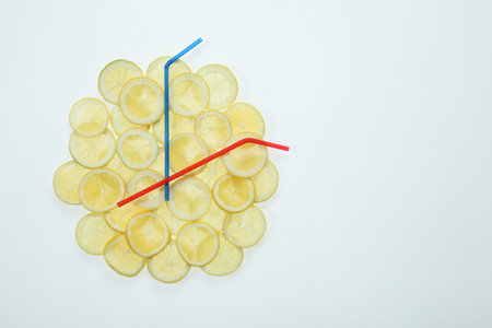 Clock made with lemon slices and cocktail straws on white background, top view. Space for text