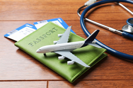 Medical tourism. Passport with tickets, stethoscope and airplane model on wooden background, closeupの写真素材