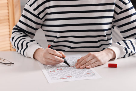 Woman circling important information with marker at white desk indoors, closeup