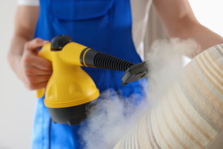Janitor cleaning pillow with steam cleaner at home, closeupの写真素材