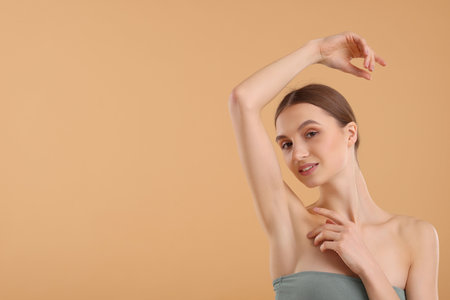 Young woman showing smooth skin after epilation on beige background, space for textの写真素材