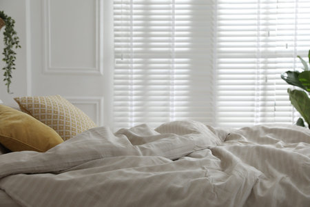 Comfortable bed with soft lines in stylish room, closeup. Interior design