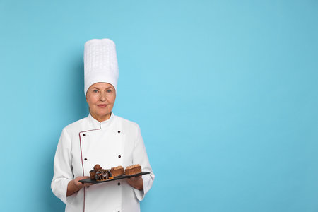 Professional pastry chef with desserts on light blue background. Space for textの写真素材