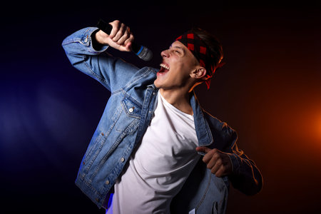 Talented singer performing on dark background with color light