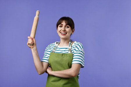 Happy woman with rolling pin on violet backgroundの写真素材