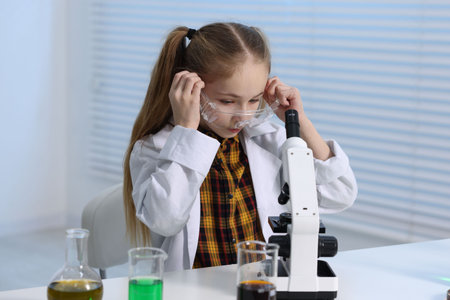 Little girl working with microscope at desk indoorsの写真素材
