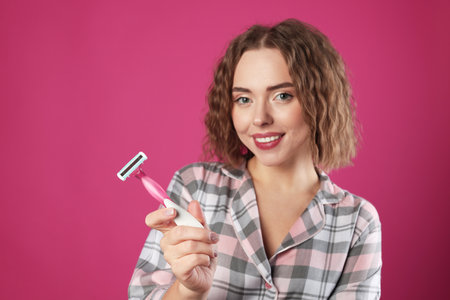 Happy woman with razor on pink background. Hair removal toolの写真素材