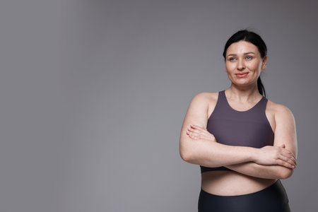 Plus size woman in gym clothes on grey background, space for textの写真素材