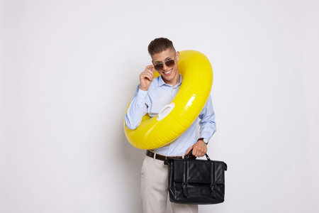Businessman with inflatable ring and briefcase on white backgroundの写真素材