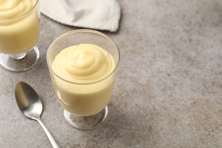 Tasty vanilla pudding served on grey table. Space for text