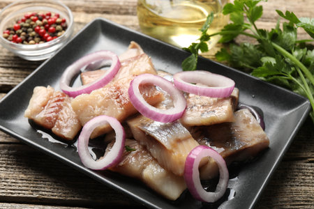 Pieces of herring with onions and parsley on wooden table, closeupの写真素材