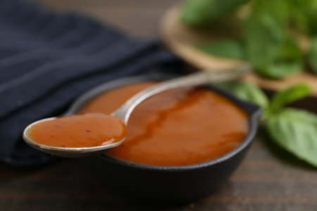 Tasty curry sauce and basil leaves on wooden table, closeupの写真素材