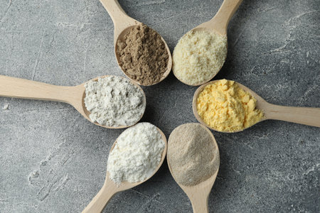 Different types of flour in spoons on grey table, flat layの写真素材