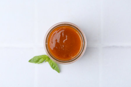 Tasty curry sauce in glass jar and basil on table, top viewの写真素材