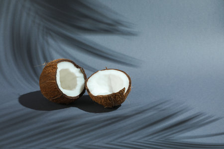 Fresh coconut and shadow cast by tropical palm on grey background. Space for textの写真素材