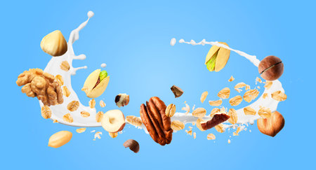 Oat flakes, nuts and splashing milk in air on light blue background. Banner designの写真素材