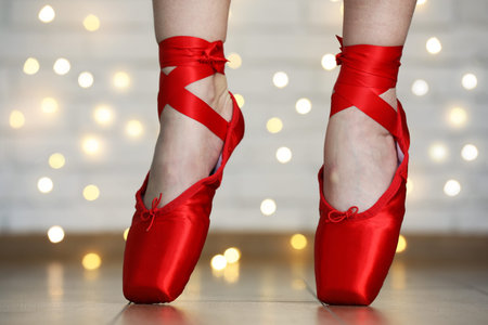 Ballerina dancing in pointe shoes against blurred lights, closeup. Bokeh effect