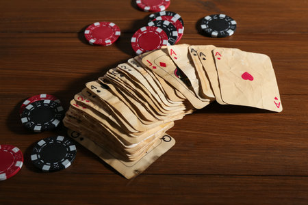 Many old vintage playing cards and poker chips on wooden table, closeupの写真素材