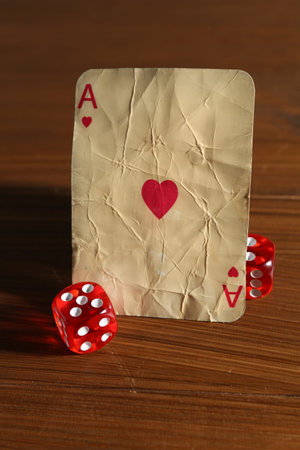 Old vintage playing card and dices on wooden table, closeup