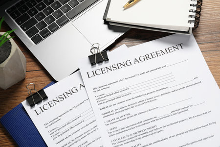 Licensing agreement documents, stationery and laptop on wooden table, flat layの写真素材