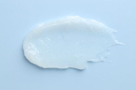 Moisturizing lip balm on light blue background, top view