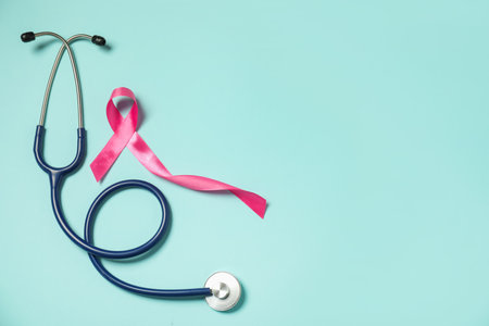 Breast cancer awareness. Pink ribbon and stethoscope on light blue background, flat lay. Space for textの写真素材