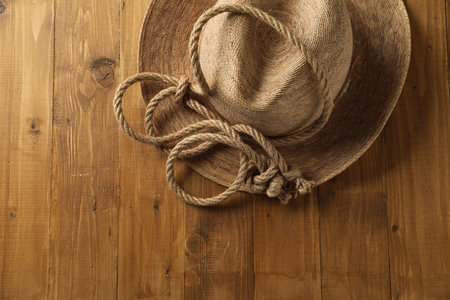 Cotton rope and straw hat on wooden background, top view. Space for text