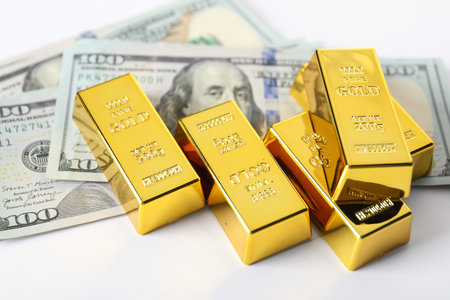 Shiny gold bars and dollar banknotes on white background, closeupの写真素材