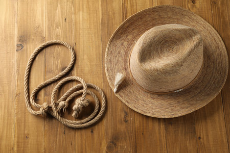 Lasso made of cotton rope and straw hat on wooden background, flat layの写真素材