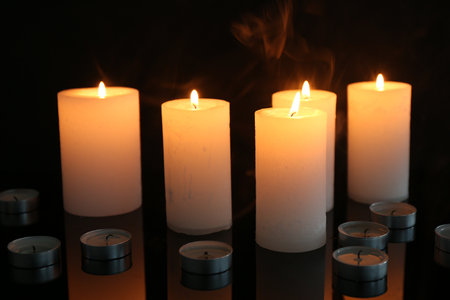 Many burning candles on mirror surface against black background, closeupの写真素材