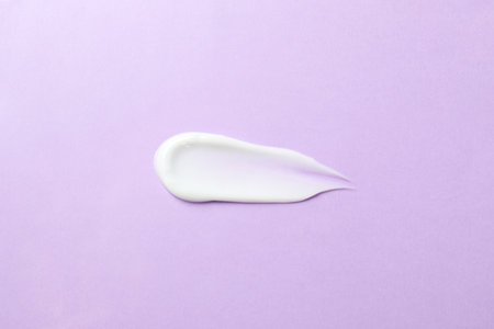 Body cream on violet background, top viewの写真素材